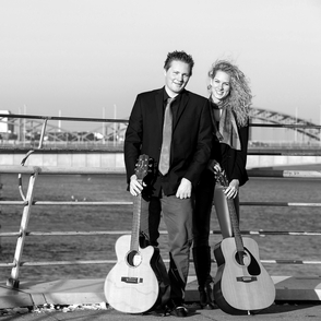 Foto des Duos in SW auf einer Brücke über einen Fluss mit Instrumenten in der Hand