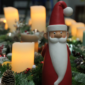 Adventsgestecke mit angez&uuml;ndeten Kerzen und einem Ton-Weihnachtsmann