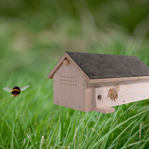 Hummelhotel auf einer Wiese mit einer fliegenden Hummel