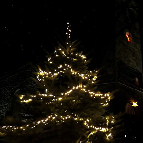 Evangelische Kirche D&ouml;nberg im dunkeln mit beleuchteten Weihnachtbaum im Vordergrund