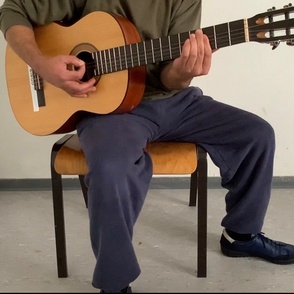 Gefangener in Anstaltskleidung spielt Gitarre