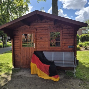 Gartenbank mit Deutschlandfahne vor einem Gartenhaus