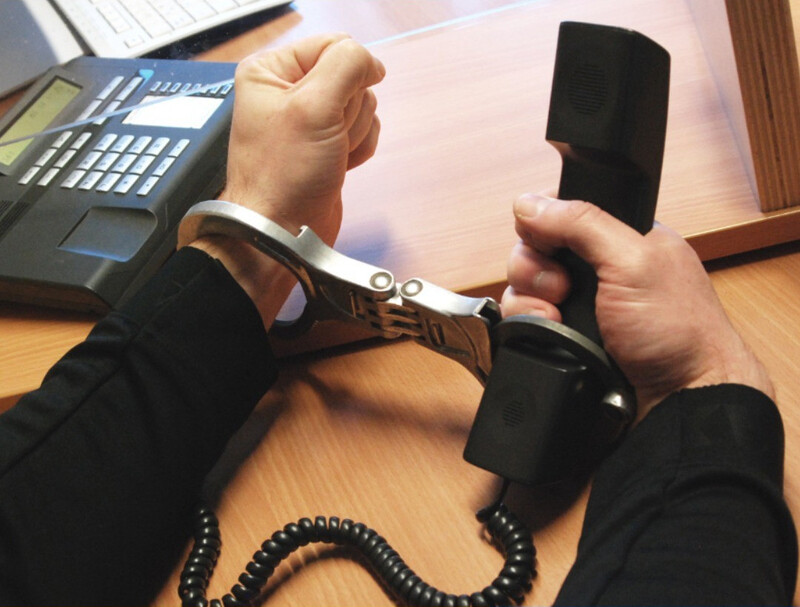 Gefangener mit Handschellen an einen Telefonhörer gefesselt