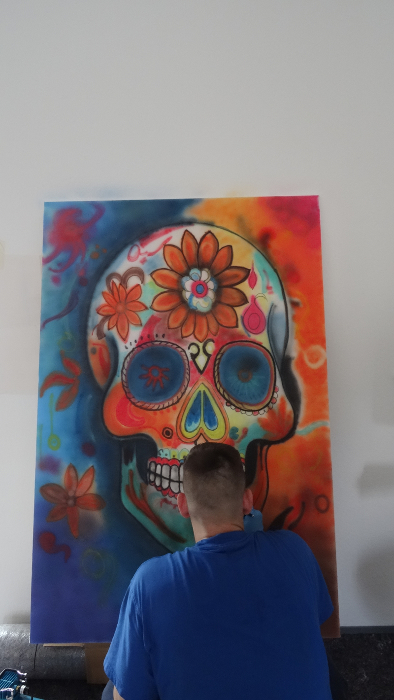 Ein Gefangenenr arbeitet an seinem Kunstwerk, einem bunten Totenschädel