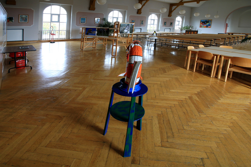 Die Aufnahme mit einem Weitwinkelobjektiv zeigt einen Überblick über die Ausstellung von Fotografien und Skulpturen in der Kirche von Haus 1.