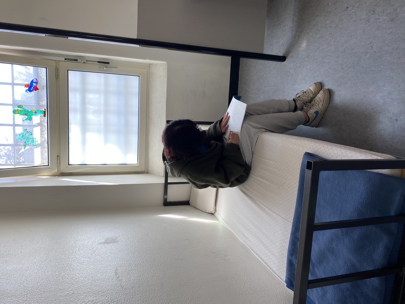 Arrestantin auf dem Bett in ihrem Haftraum schreibt einen Text