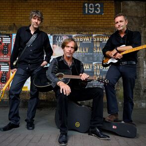 Foto der Band in einer Unterf&uuml;hrung vor Plakaten mit Instrumenten