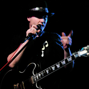 Portrait des K&uuml;nstlers mit Mikrofon und Gitarre