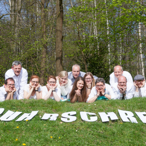 Chor "Ruhrschrei, Mitglieder liegen auf einem grünen Hügel, auf dem die Buchstaben Ruhrschrei zu sehen sind