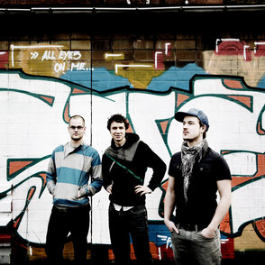 Gruppenfoto der drei K&uuml;nstler vor einem Grafitti