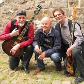 Gruppenbild mit Instrumenten vor einer Bruchsteinmauer